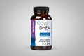 Bottle of DHEA supplement with label on a gray background