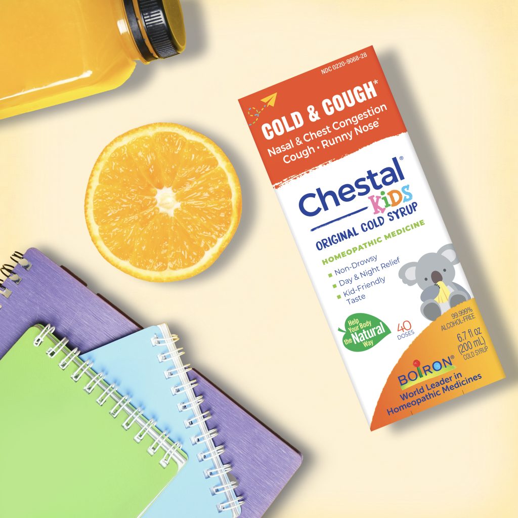 Chestal Kids cold and cough syrup package with an orange and notebooks on a light background
