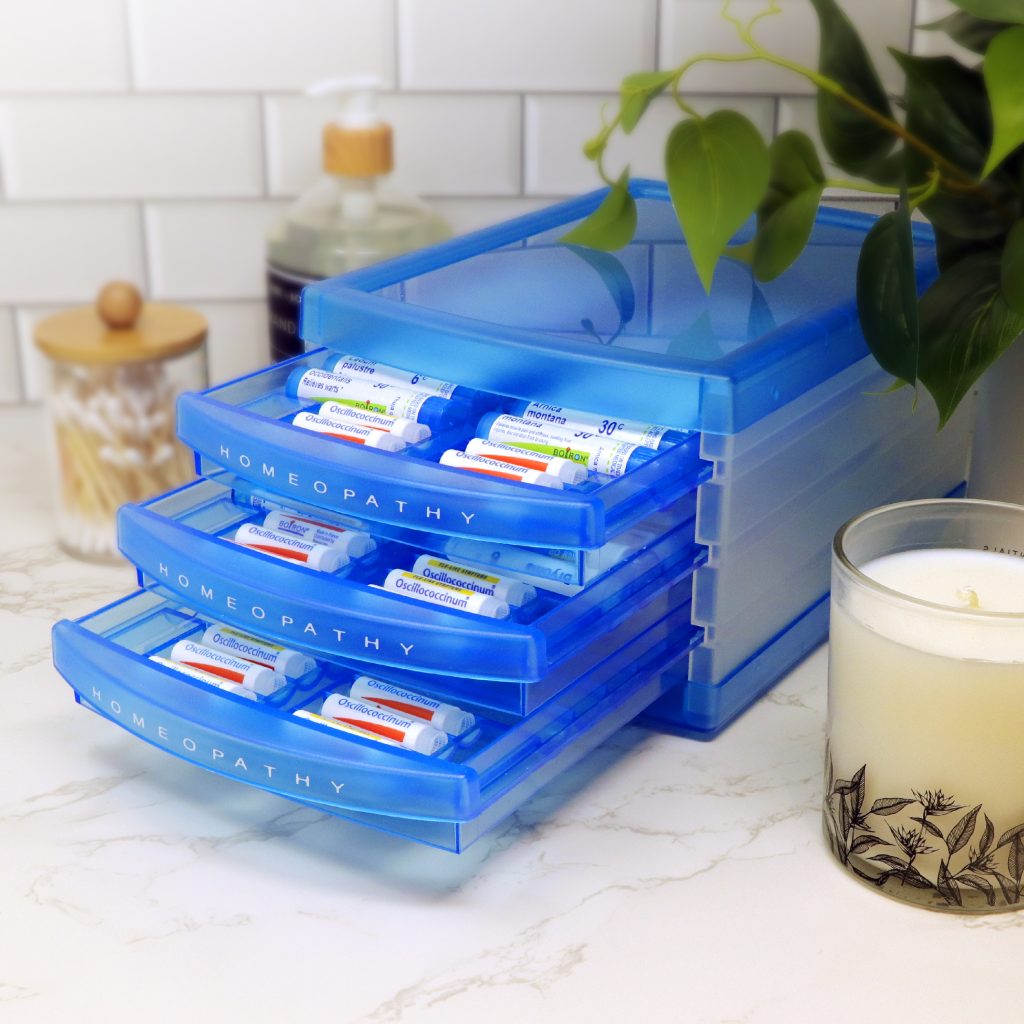 Blue homeopathy organizer with containers on a kitchen counter.
