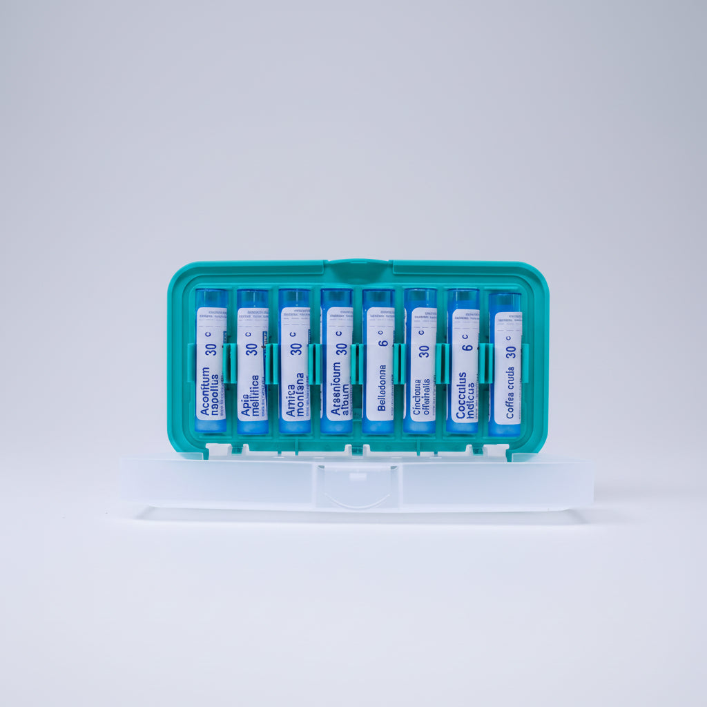 Set of homeopathic medicine vials in a green and white container on a white background