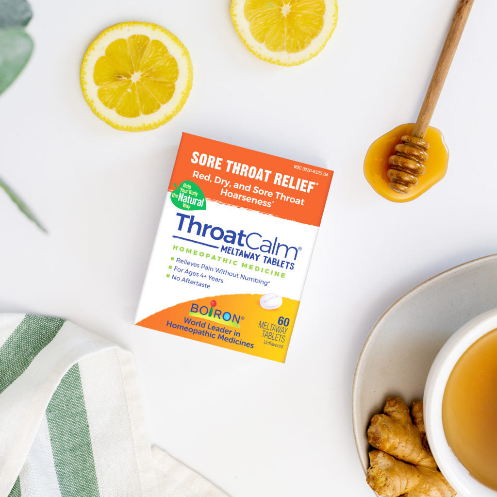 Boiron ThroatCalm packaging with lemons, honey, and tea on a white background