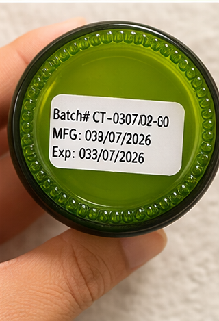 Green jar lid with batch number, manufacturing date, and expiration date label held by a hand.