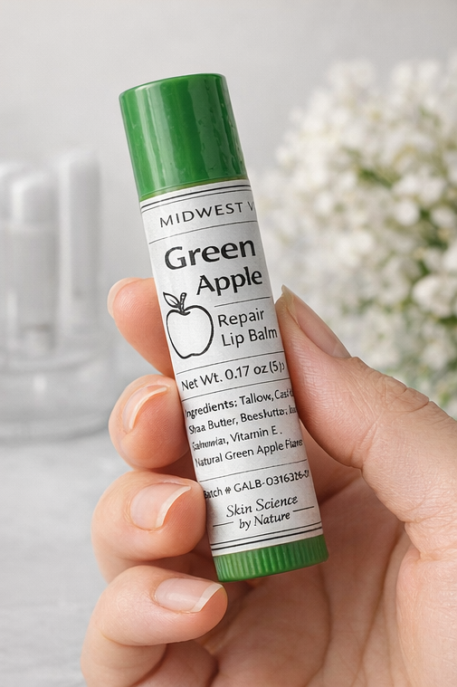 Hand holding a green apple lip balm with a blurred background