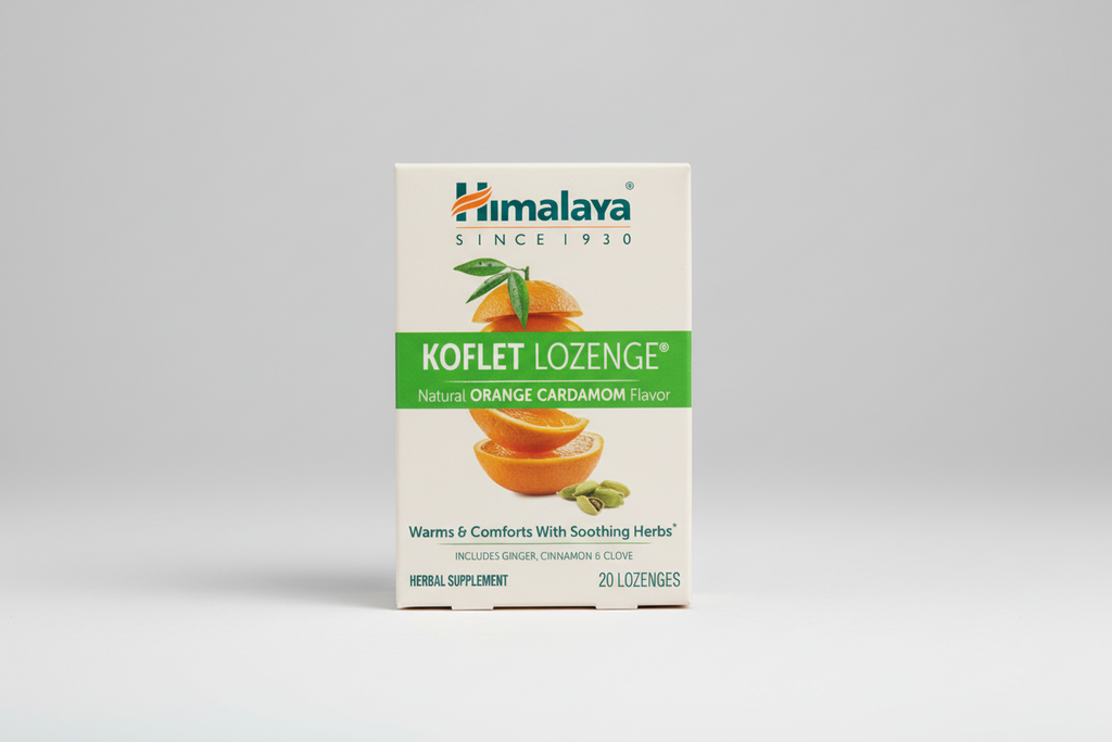 Himalaya Koflet Lozenge packaging with oranges and cardamom on a beige background