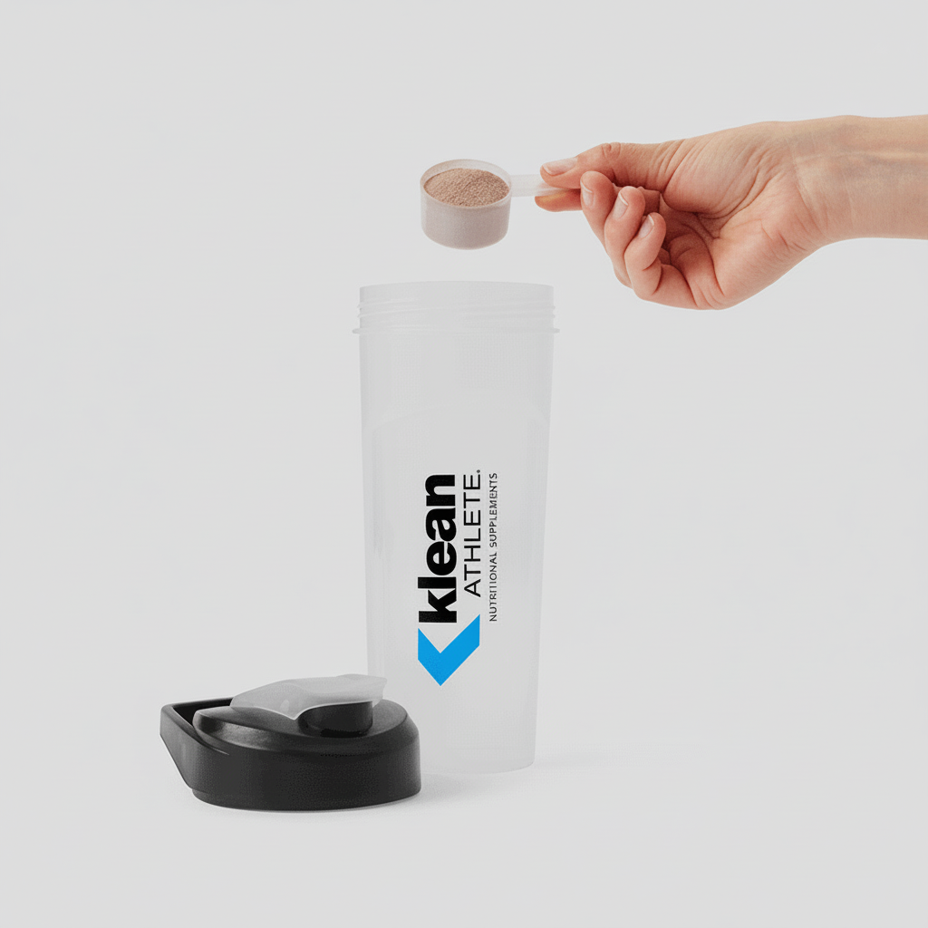 Hand pouring a supplement into a Klean Athlete container on a light gray background
