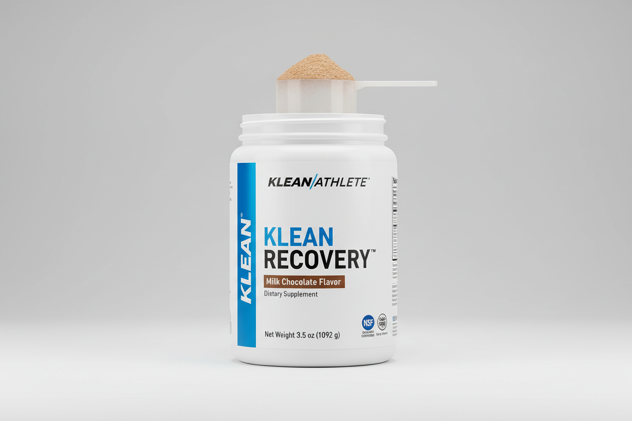 Person holding a Klean Athlete protein powder container with lemons on a table.