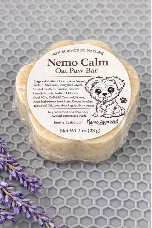 Nemo Calm Oat Paw Bar soap on a gray honeycomb background with lavender flowers.