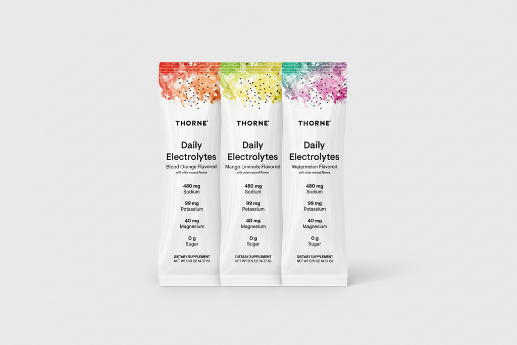 Three Thorne Daily Electrolytes packets with colorful labels on a black background