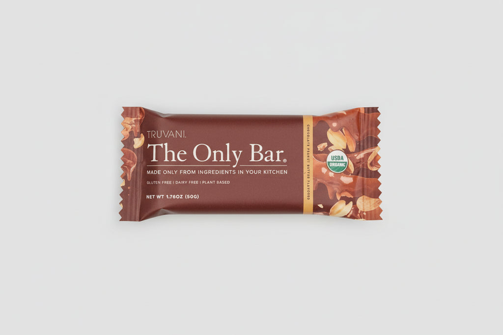 Truvani The Only Bar surrounded by chocolate pieces on a pink background