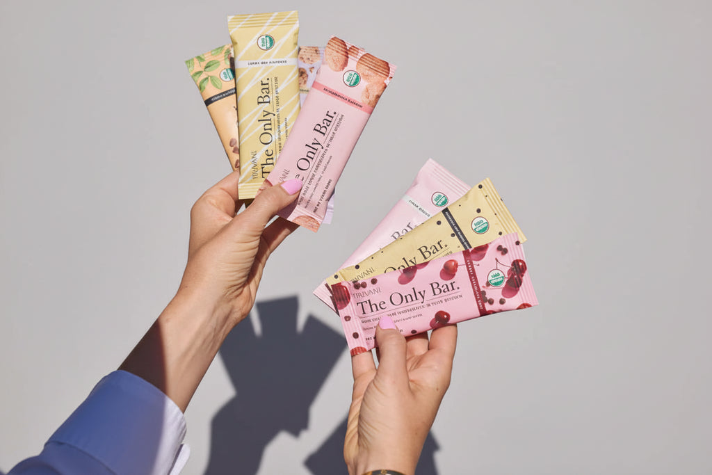 Hands holding various flavors of 'The Only Bar' with a pool background and USDA Organic logo.