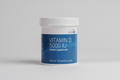 Vitamin D supplement container with blue label and white cap on a white background